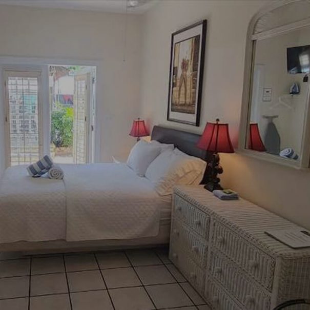 Room 12, a view of the queen size bed and the door open to the sunny pool patio.